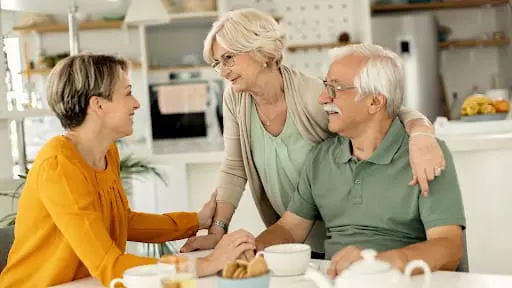 Happy woman visiting her senior parents and communicating with them at home.