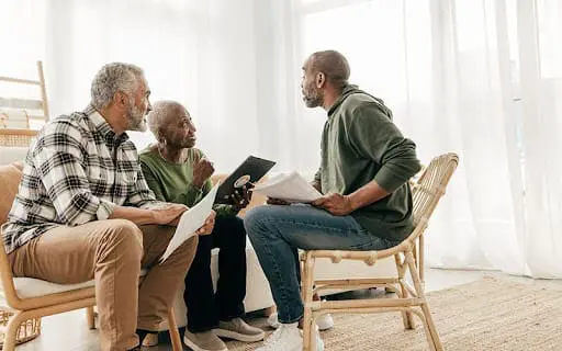 Mature man going through paperwork on the meeting with senior couple