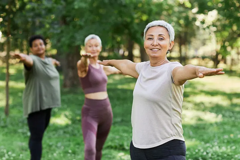 Smiling senior woman enjoying sports workout outdoors and looking at camera