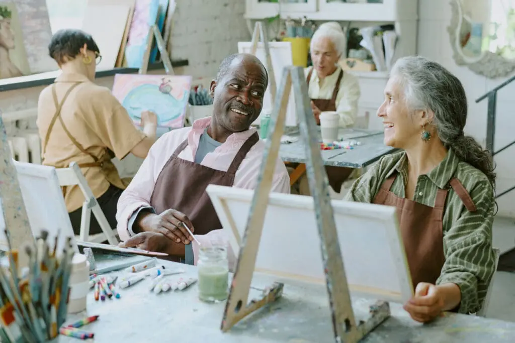 Two seniors painting and talking about the benefits of moving to assisted living at The Heritage at Brentwood®.
