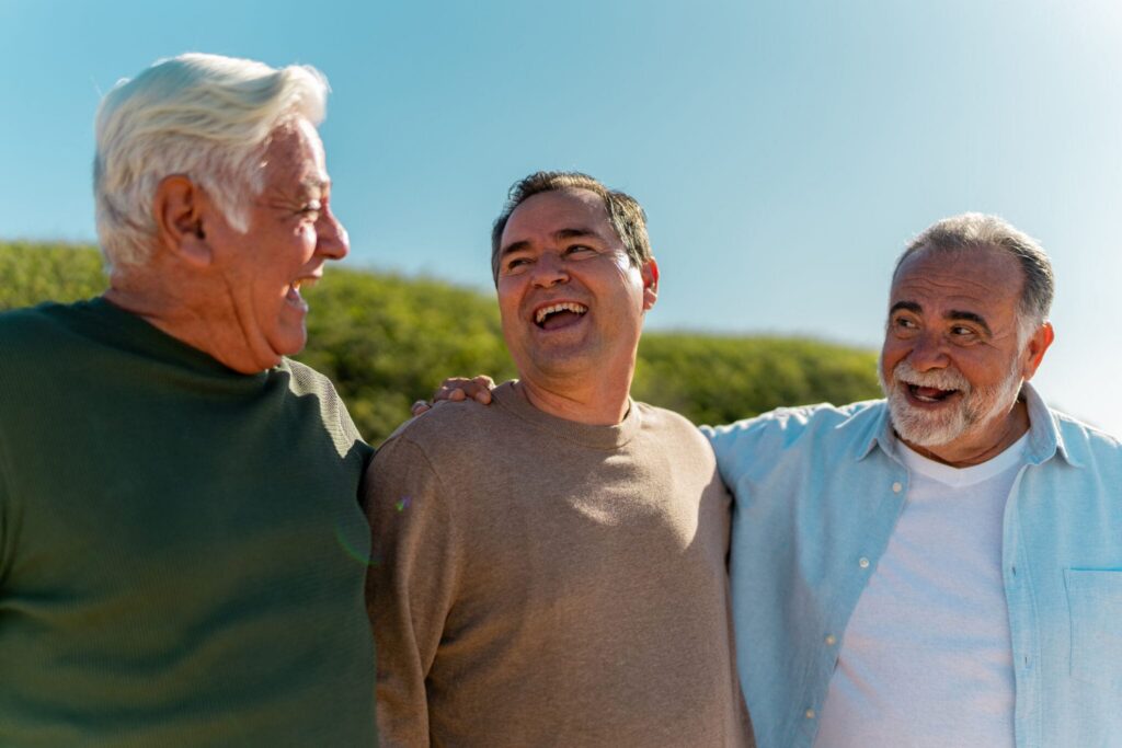 Senior men smiling and talking on the beach