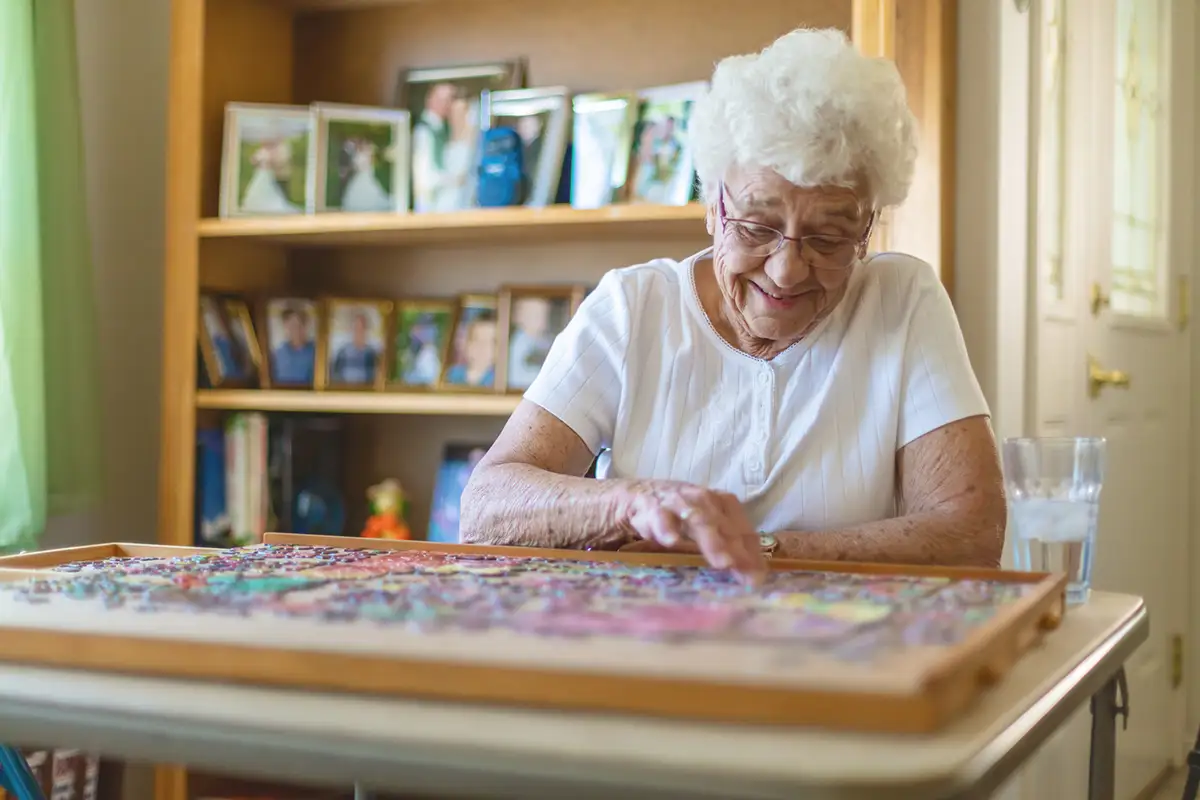 Memory Care Heartfelt Connections. Resident putting together a puzzle.