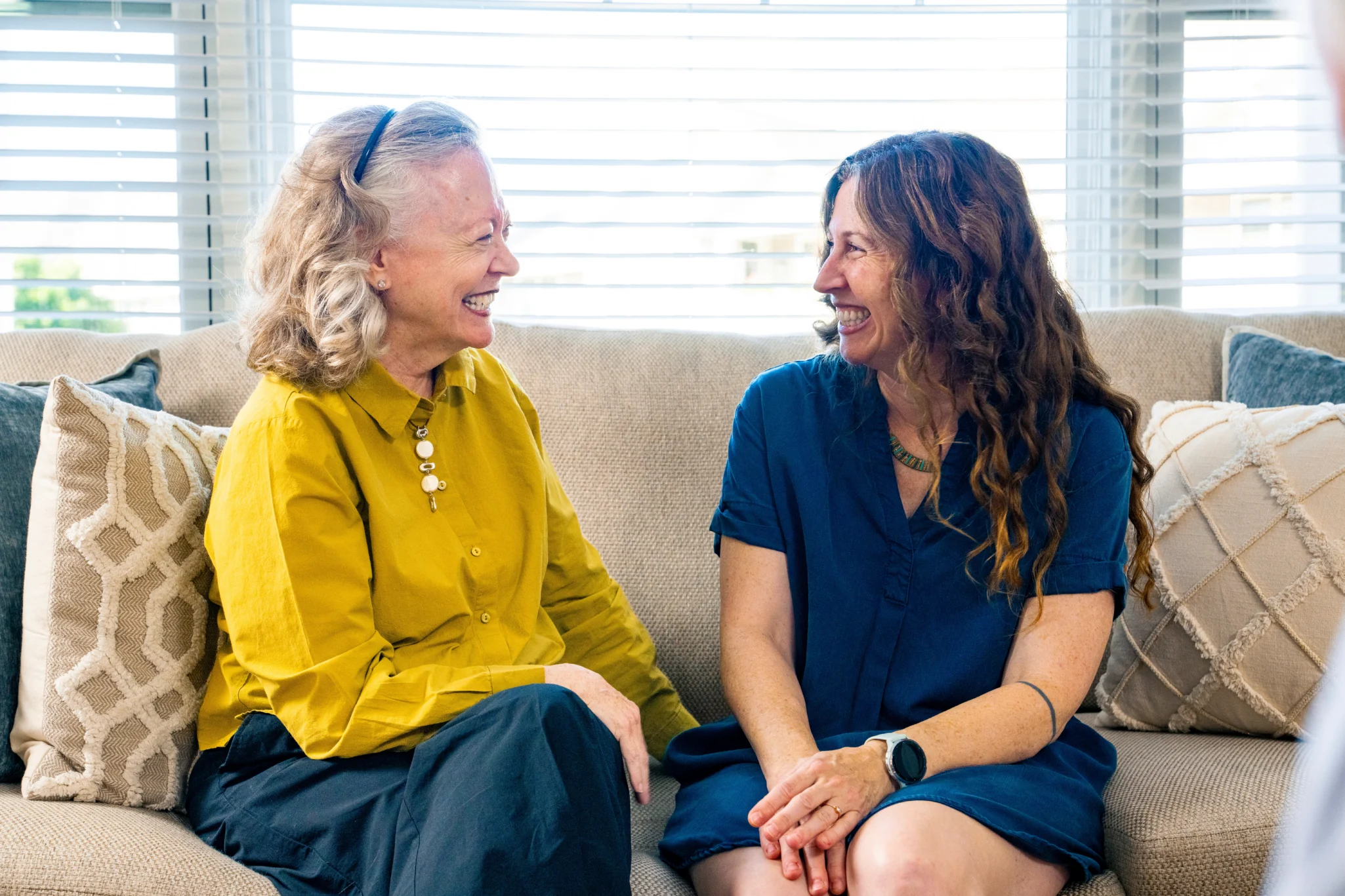 senior woman and woman talking on couch