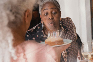 A senior woman blowing out candles on a cake