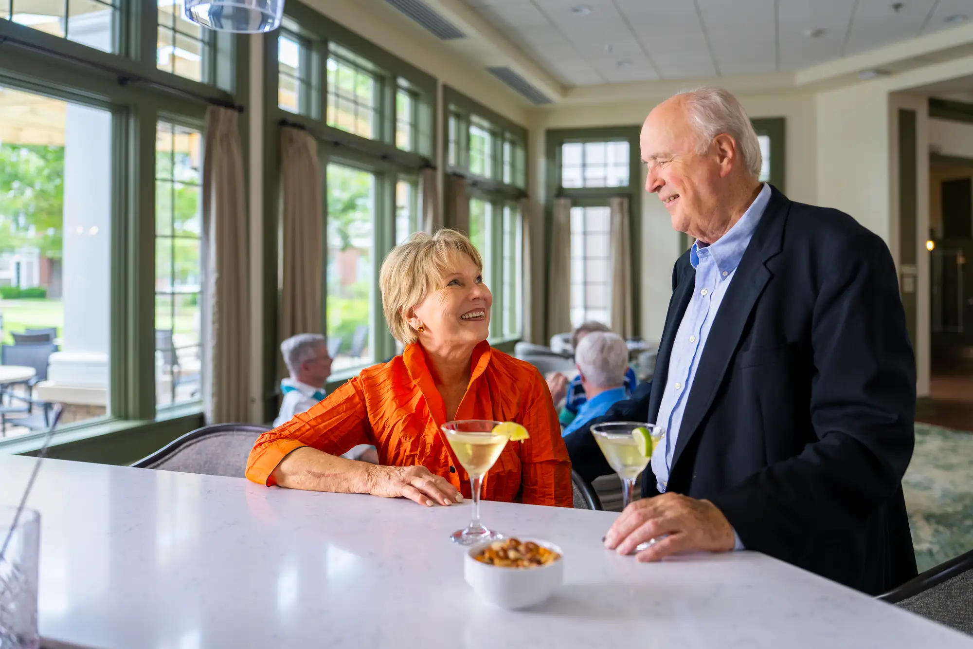 An image of a senior couple touring The Heritage at Brentwood while drinking cocktails during happy hour and discussing the cost of senior living in TN. 