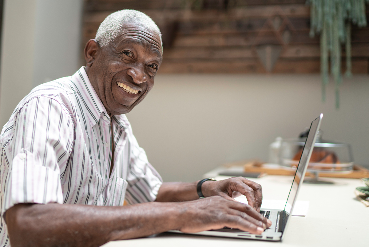 retired senior man smiles as he works in his computer