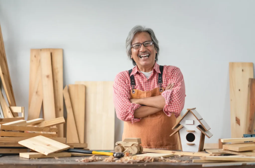 senior man crossing arms and smiling in woodshop